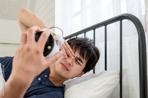 Asian attractive young man turn off alarm clock ringing in the morning. 
