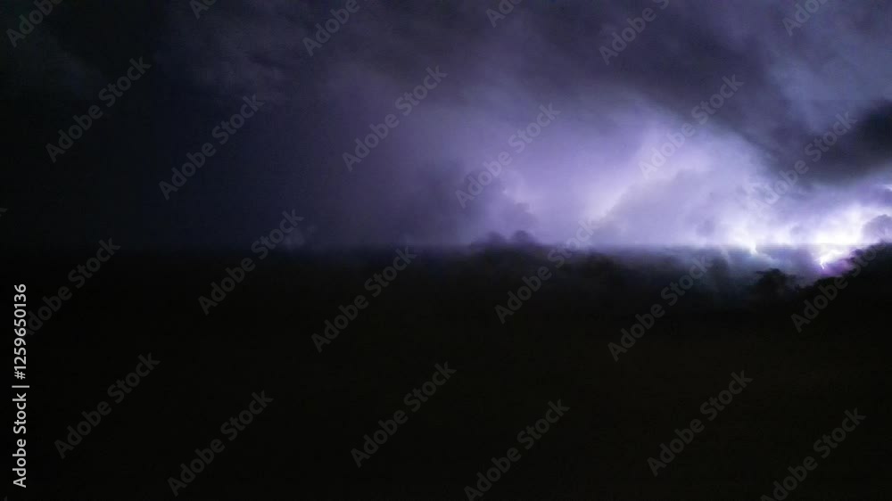 Breathtaking low angle footage of the lightning flashing in the dark night sky during a thunderstorm