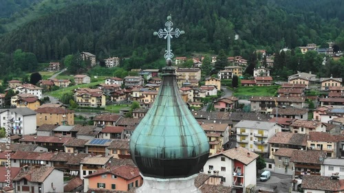 Drone flying near bell tower of Church of San Lorenzo, town in background, Rovetta, Bergamo in Italy. Aerial lateral view, Close-up photo