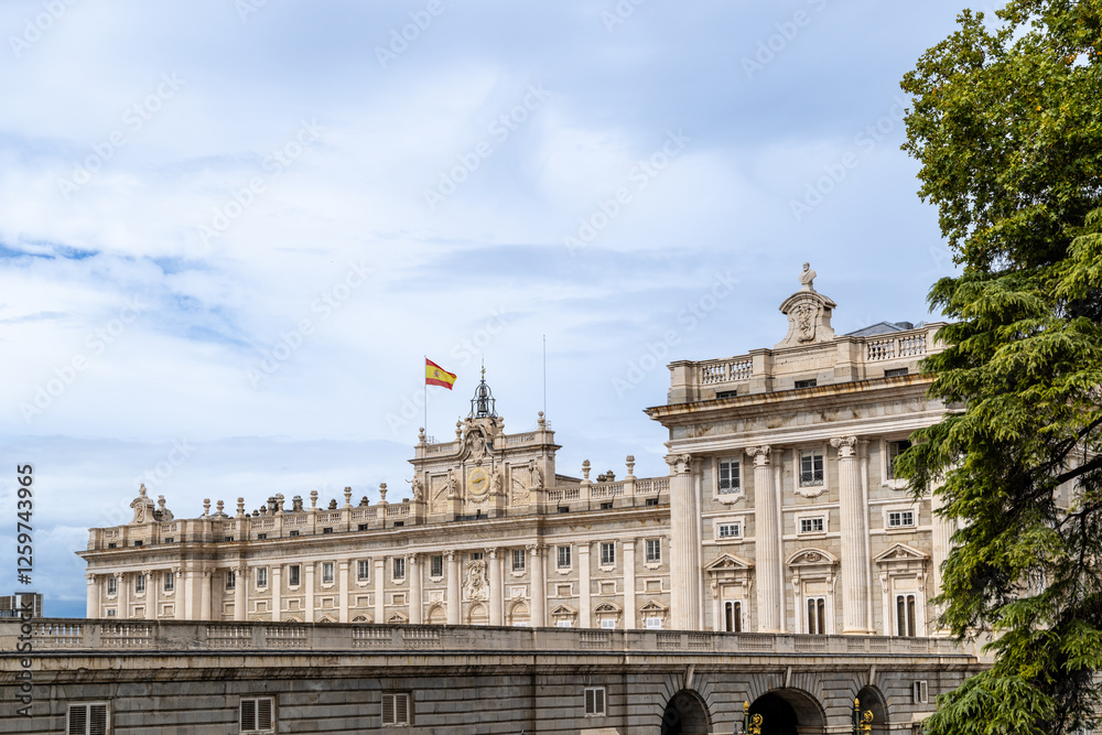 Naklejka premium Madrid, Spain - october 02, 2024: Facade of the Royal Palace of Madrid with tourists walking around in Madrid, Spain