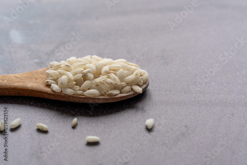 White short grain rice in wooden spoon on dark background. White rice on dark background
