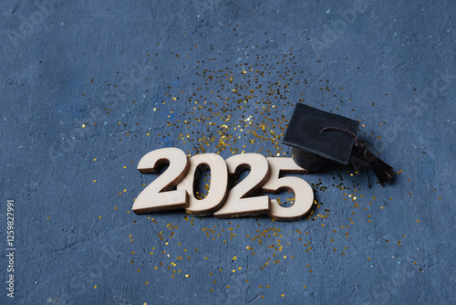 Graduation cap on wooden number 2025 on dark background. Class of 2025 concept