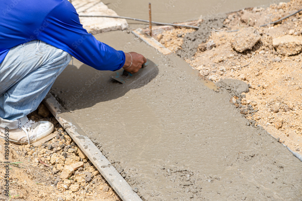 A contruction woker uses trowel to plaster wet concrete A contruction woker uses trowel to plaster wet concrete