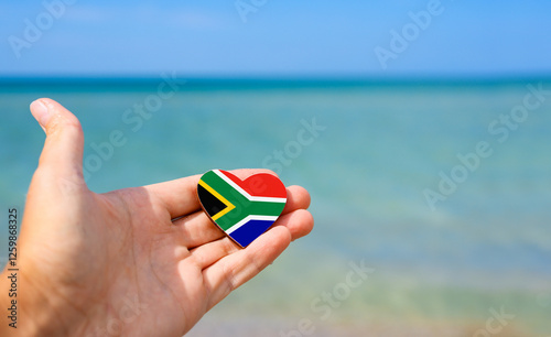 Flag of South Africa in hand against the sea. Summer vacation in South Africa