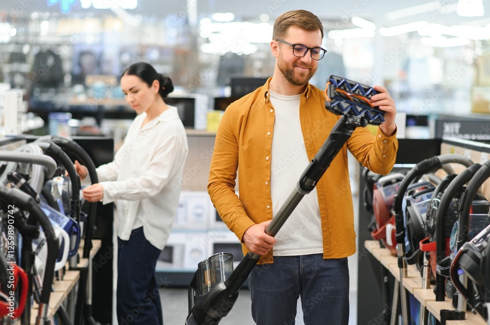 Young beautiful couple buying new vacuum cleaner at tech store. Having fun shopping time Young beautiful couple buying new vacuum cleaner at tech store. Having fun shopping time