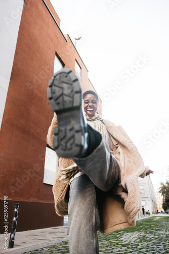 Young stylish woman kicks towards camera in playful street scene