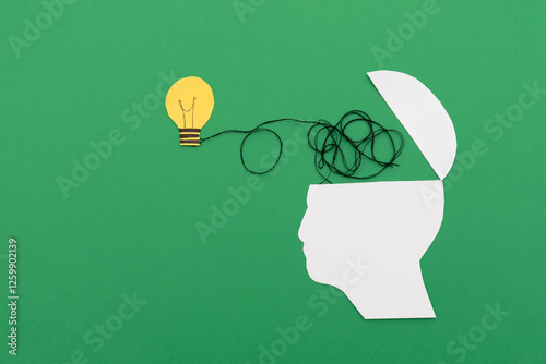 Tangled thread connecting an open head silhouette to a light bulb on green background, problem-solving and Creative Thinking concept