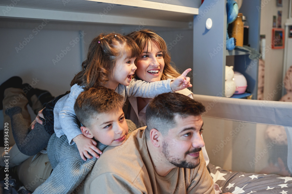 Happy family playing and laughing together on a bed in a cozy bedroom Happy family playing and laughing together on a bed in a cozy bedroom