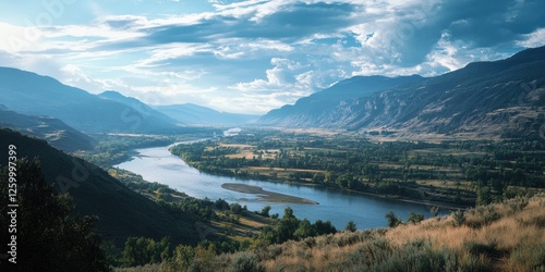 Sweeping view of a valley and river, with a backdrop of mountains under a partly cloudy sky. photo