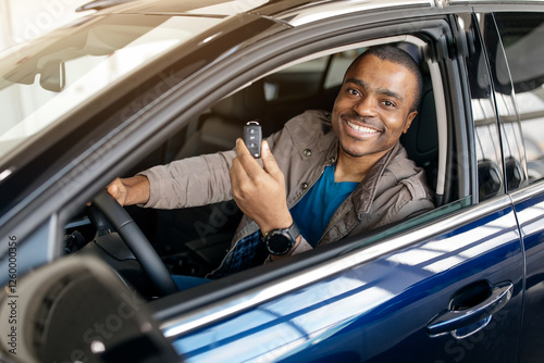 Car showroom, auto retail concept. Happy african man in casual outfit driving luxury white car, showing key, african american driver enjoying brand new comfortable automobile, copy space. High quality