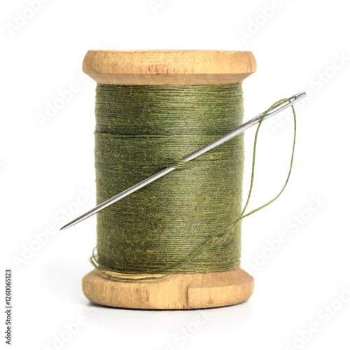 Old Single wooden spool of thread olive green color and needle. Simple design of thread closeup white background photo