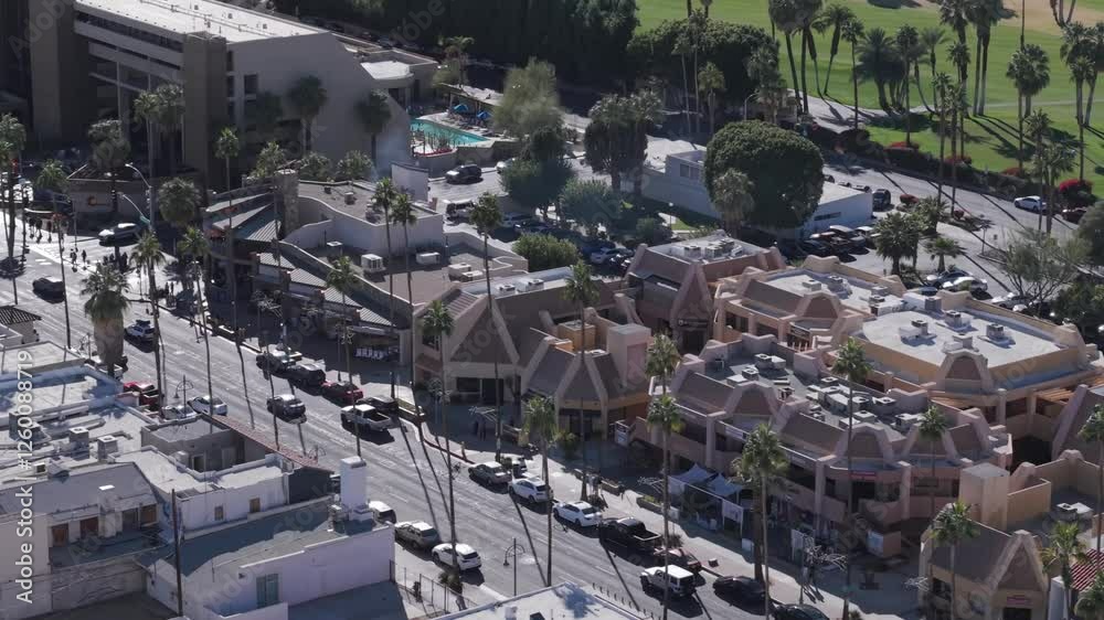 Car traffic on a main street lined with palm trees by a golf course in Palm Springs California - aerial flyover Car traffic on a main street lined with palm trees by a golf course in Palm Springs California - aerial flyover