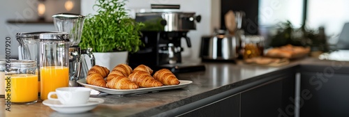 Modern kitchen setup with breakfast being served, including fresh croissants and juice