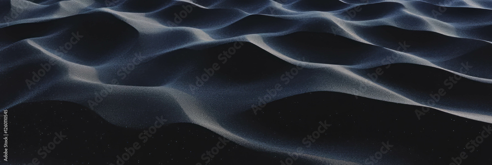 Fototapeta premium Texture of black sand interspersed with fragmented volcanic rock casts deep shadows