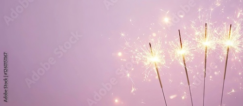 Fototapeta Naklejka Na Ścianę i Meble -  Golden sparklers illuminated against a soft light purple background arranged on the left side, providing ample space for text on the right.