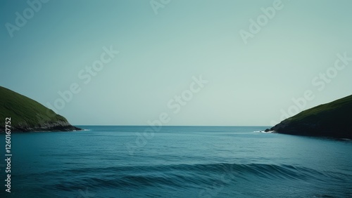 A tranquil seascape showcasing calm waters and a lush green hillside under a soft, overcast sky. Ideal for projects related to nature, serenity, or coastal beauty