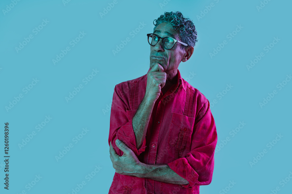 Senior man with red shirt posing in studio. Funny senior man with different expressions posing on colored backgrounds. Studio shot with colored gel lights. Senior man with red shirt posing in studio. Funny senior man with different expressions posing on colored backgrounds. Studio shot with colored gel lights.