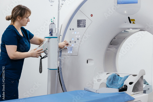 A medical nurse, doctor push buttons of a modern CT scanner while attending to a patient in a medical facility. The scene highlights advanced technology and healthcare support for diagnostic imaging