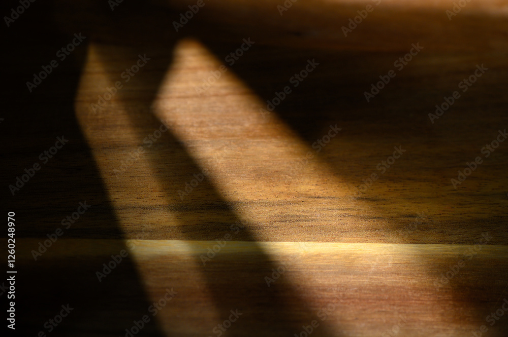 Play of light and shadow on a wooden surface creates a warm, textured ambiance during the afternoon