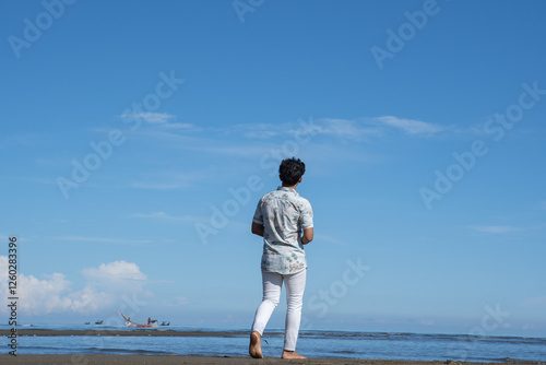 A man walks on a sandy beach at sunrise