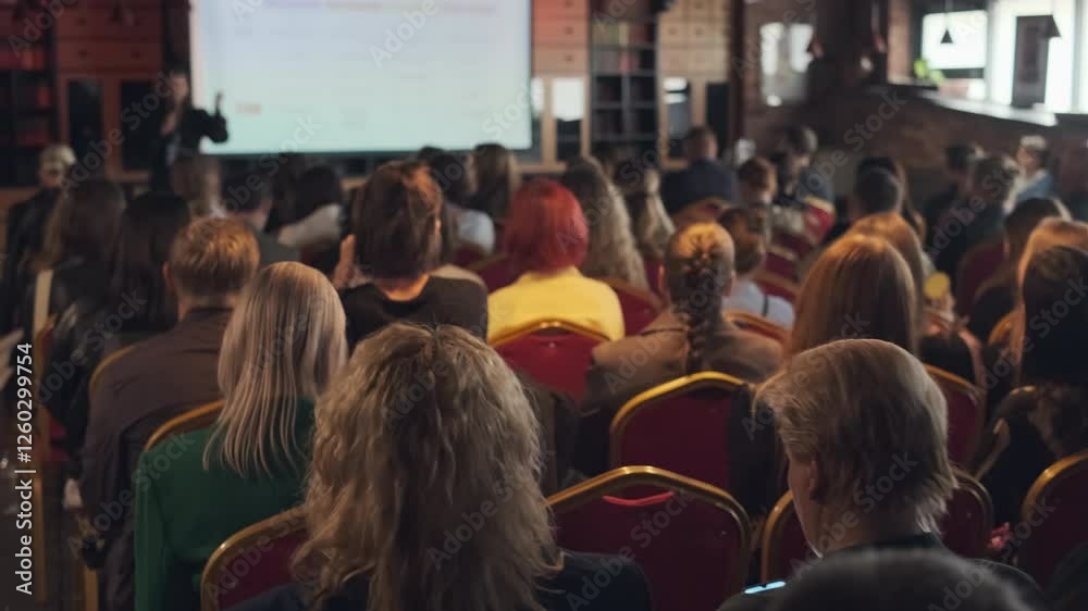 Large group of people attending educational event in comfortable indoor venue with speaker.