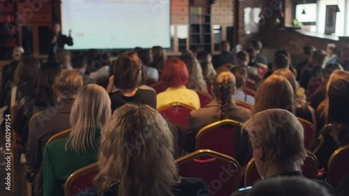 Large group of people attending educational event in comfortable indoor venue with speaker.