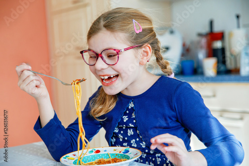 Obraz na płótnie Little school girl eat pasta spaghetti with tomato bolognese with minced meat. Happy preschool child eating fresh cooked healthy meal with noodles and vegetables at home, indoors. w salonie