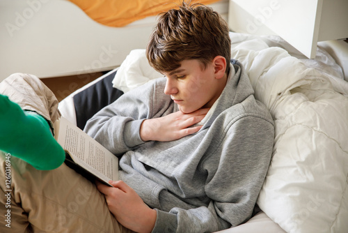 Wallpaper Mural Young handsome smiling teenager reading book at home. Happy child studying. Torontodigital.ca