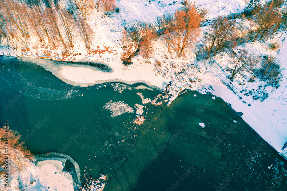 Top view of an unfrozen narrow stream on a sunny winter day