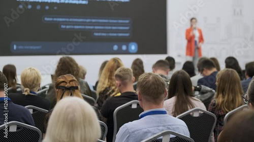 Conference audience attentively listening to a presenter giving a talk in professional setting