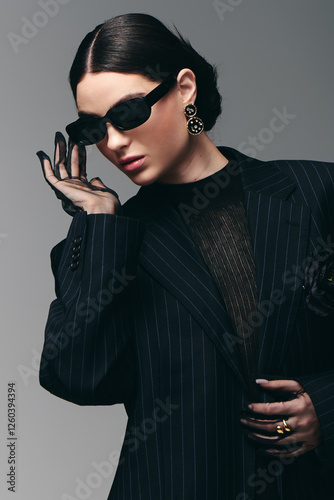 Stylish young woman poses confidently in elegant fashion against minimalist backdrop