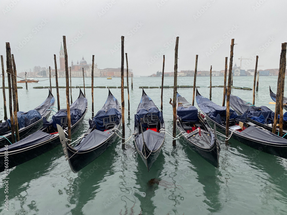 Gondolas boats under the rain moored at San Marco in the Grand Canal, Venice, Italy. Gondolas boats under the rain moored at San Marco in the Grand Canal, Venice, Italy.