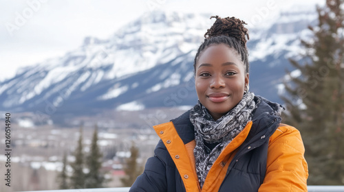 African woman wearing a coat sitting on a bench enjoying the view of the Canadian Rockies