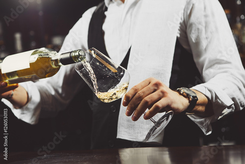 Sommelier Pours White Wine Into Glass, Close-up. photo