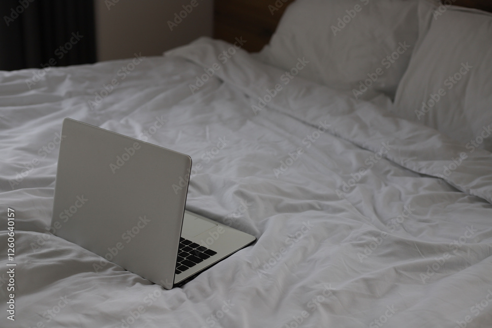 Fototapeta premium white laptop stands on a bed with white linens