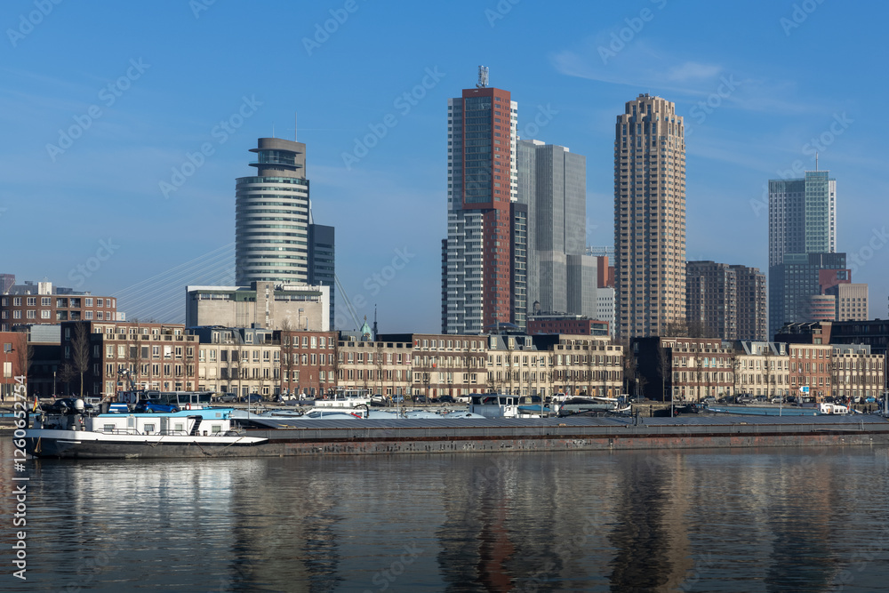 Naklejka premium Skyline with skyscrapers of Rotterdam with in the foreground typical dutch architecture with brick facades of a few stories high. cargo ships in the maashaven.