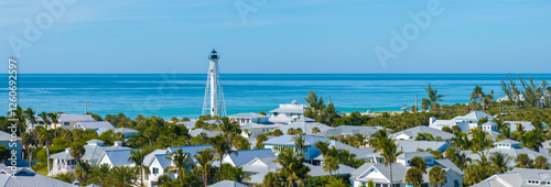 Fotografi Famous lighthouse on ocean shore and expensive residential houses in island smal
