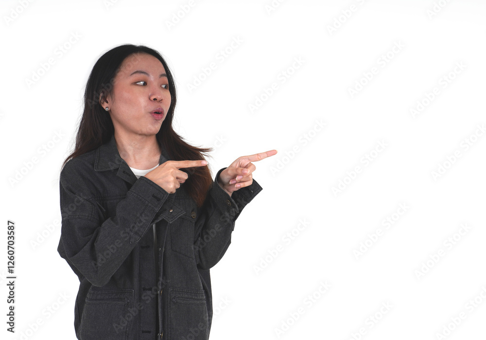 Excited young asian woman wearing black denim jacket pointing or showing something with both hands isolated on horizontal copy spaced white background. Excited young asian woman wearing black denim jacket pointing or showing something with both hands isolated on horizontal copy spaced white background.