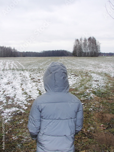 Dziecko patrzące na zimowy wiejski krajobraz photo