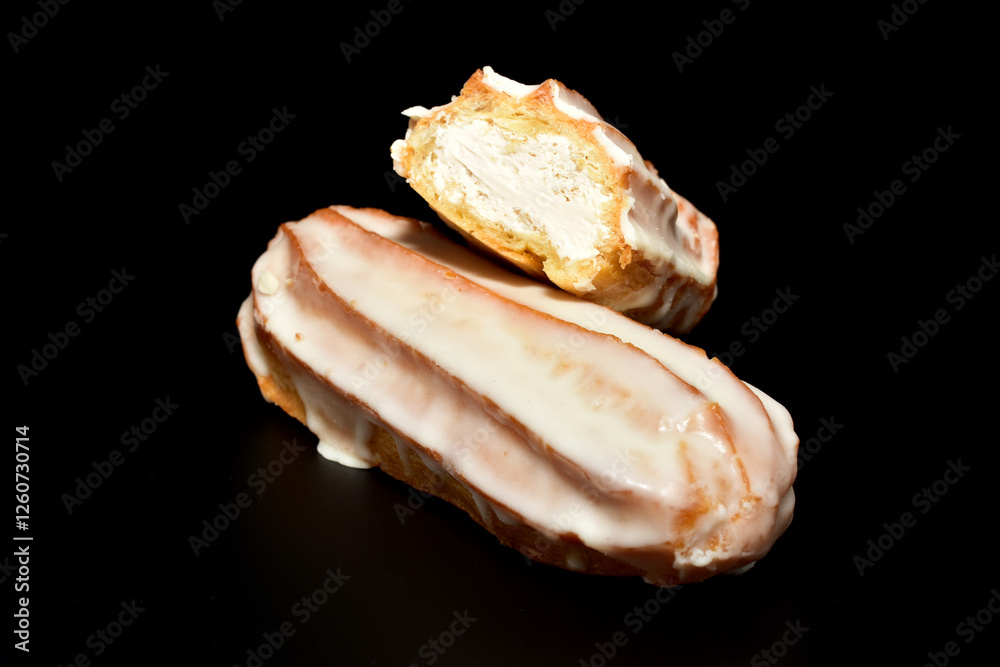 Eclair cake with delicious cream lies on a black background. Eclair cake with delicious cream lies on a black background.