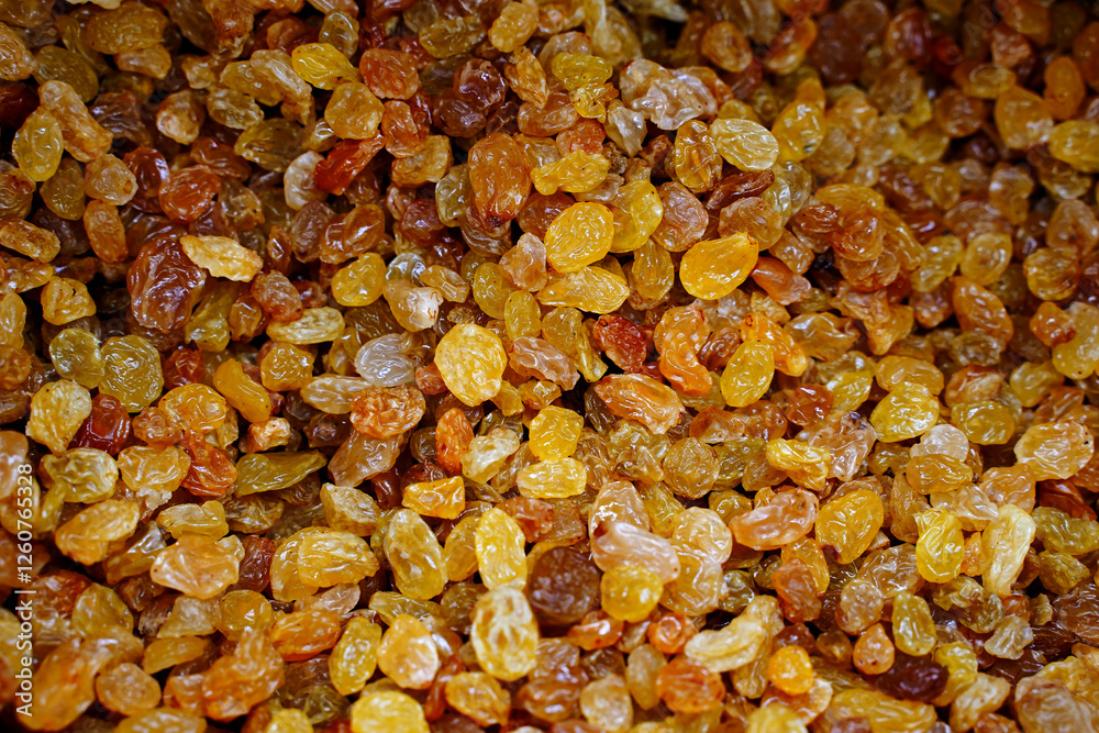 Dried yellow golden raisins as background. Pile of sweet and dry raisins for dessert. Organic golden raisins texture. Top view. Dried yellow golden raisins as background. Pile of sweet and dry raisins for dessert. Organic golden raisins texture. Top view.