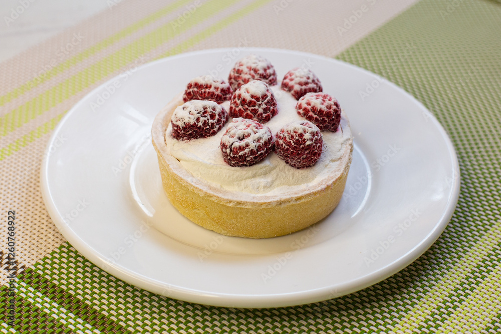 Strawberry tart on a white plate on a green tablecloth
