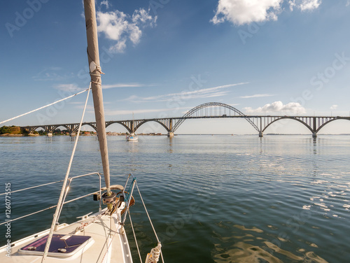 Sailboats passing Queen Alexandrine bridge, road arch bridge crossing Ulv Sund Strait between Zealand and Møn, Denmark