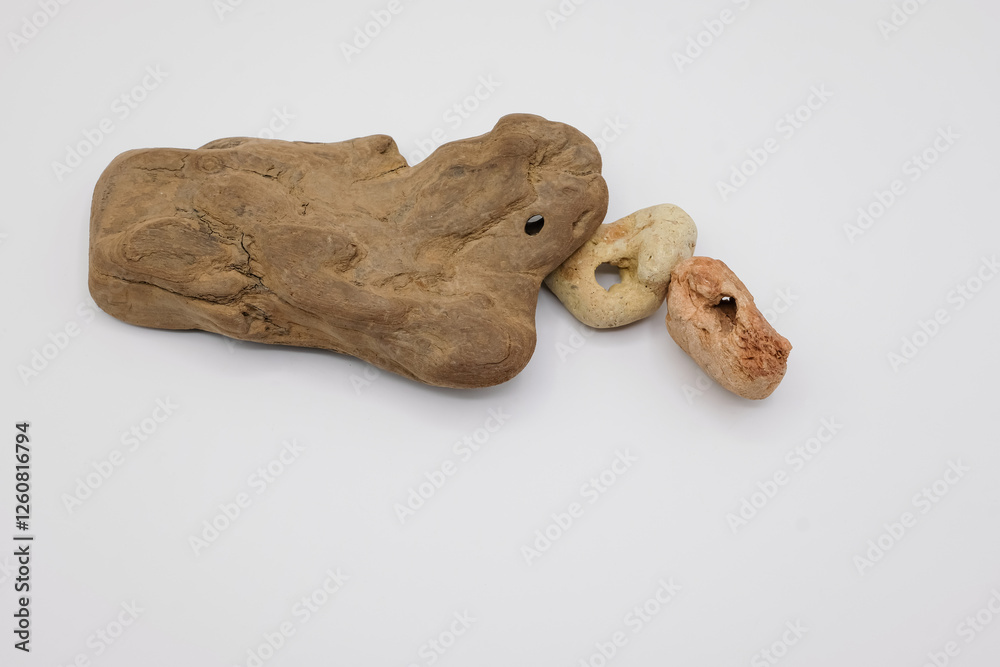 Hag stones. Piece of driftwood and two pebbles with natural holes, on the white background. Nature’s art, mystical and spiritual symbolism, luck and protection. Copy space. Hag stones. Piece of driftwood and two pebbles with natural holes, on the white background. Nature’s art, mystical and spiritual symbolism, luck and protection. Copy space.