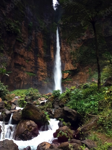 Tranquil scene of Kapas Biru waterfall with its cascade river in long exposure shot, a waterfall from a 100 meters cliff originating from a spring at the foot of Mount Semeru in Lumajang, East Java. photo