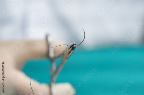 Doctor hand wear sterile gloves and surgery scissor stitching up wound after surgery.Plastic surgeon placing sutures after plastic surgery in operating room.Nurse teaches the technique of suturing.