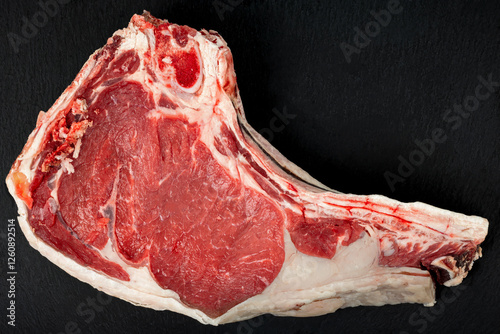 Large raw veal chop on a dark background.