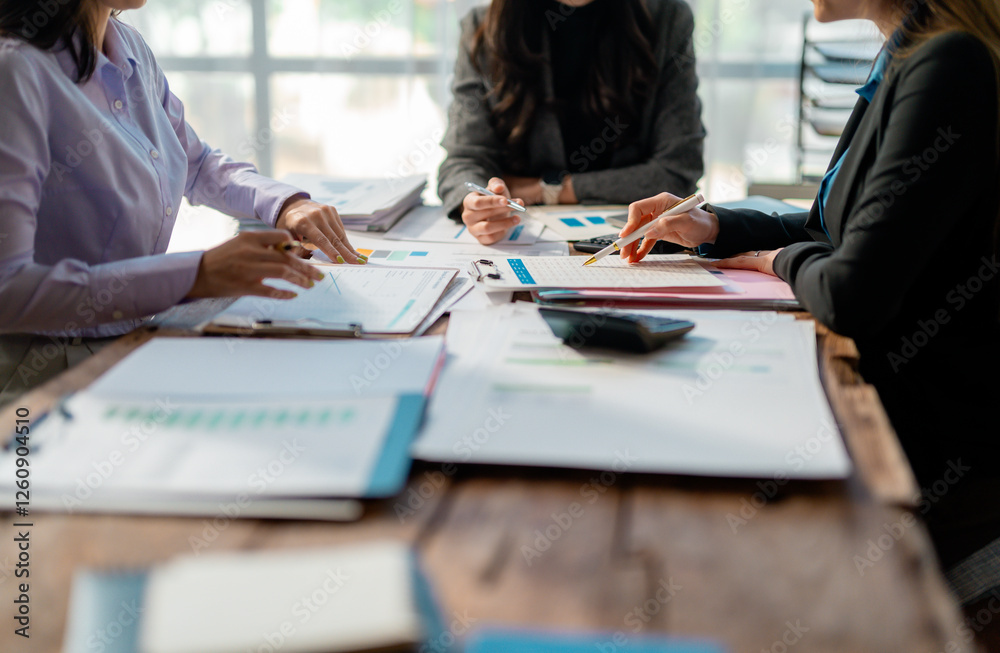 Fototapeta premium Business team working together on a project discussing company financial reports using data sheets and pointing at charts to make investment and development decisions