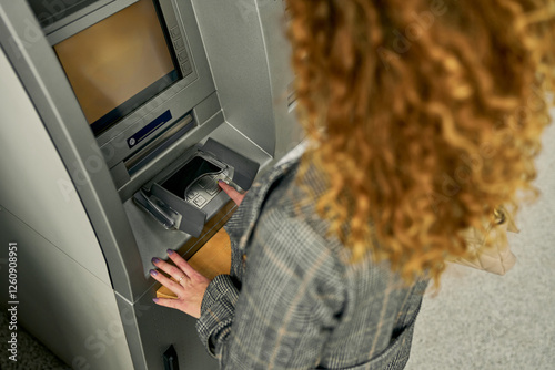 Capturing a moment of security, the young woman enters her PIN with a sense of assurance, ensuring a protected and confidential transaction at the ATM.