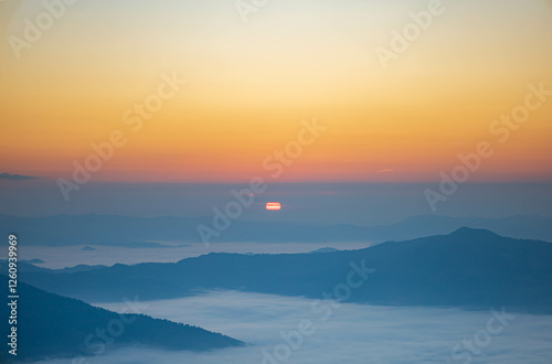 The stunning view from a tourist's standpoint as they go down a hill on a foggy trail with a hill and a background of a golden sky in Forest Park, Thailand. Rainforest. Bird's eye view. Aerial view.